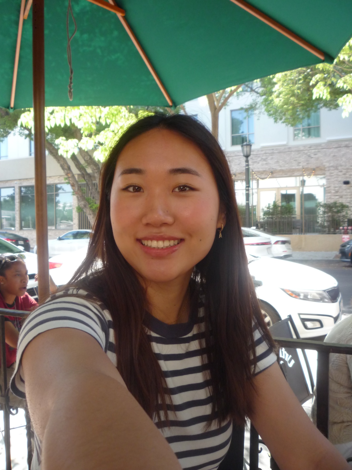 Andrea Li smiling outdoors under a green umbrella